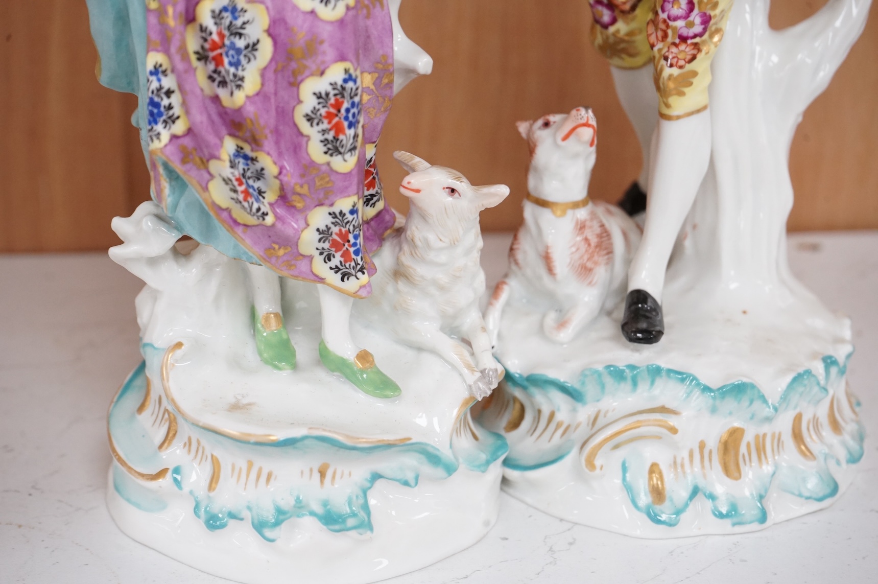 A pair of Derby style figures of a lady holding a bird cage and a gentleman holding a bird, tallest 23cm high